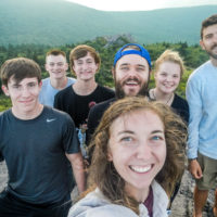 A group of teens smile as they are happy to be finished hiking.