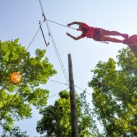 A young girl makes the "Leap of Faith" jump on the high ropes course at Camp Canaan.