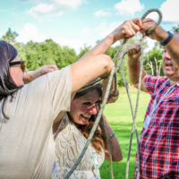 A lady works to untie herself from a rope in a team building exercise.