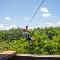 A kid zip lining across a gorge.