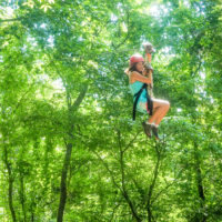 A girl zip lining high up in the trees.