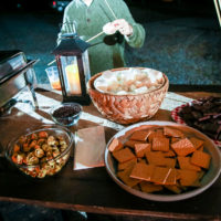 A photo of graham crackers and marshmallows on a table, outdoors. These items are for guests to make smores at the nearby campfire.