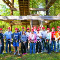 A large group of people pose before climbing the tower and beginning their team building experience.