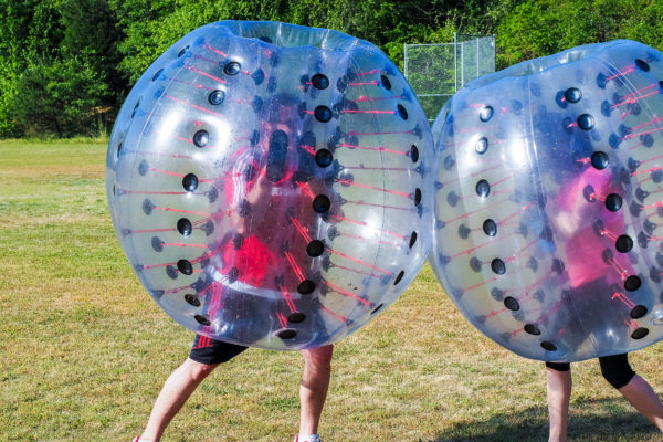 Two people collide wearing bubble soccer balls.