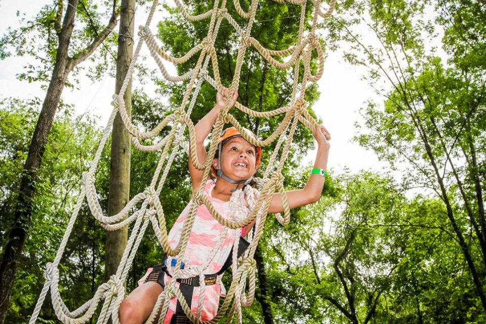 female summer camper climbs outdoor ropes element