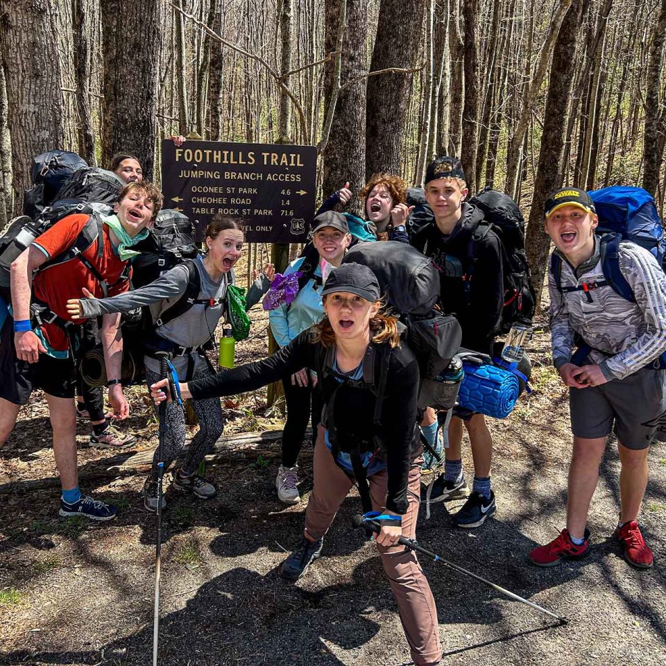 TLC counselor and campers pose in front of sign that reads Foothills Trail