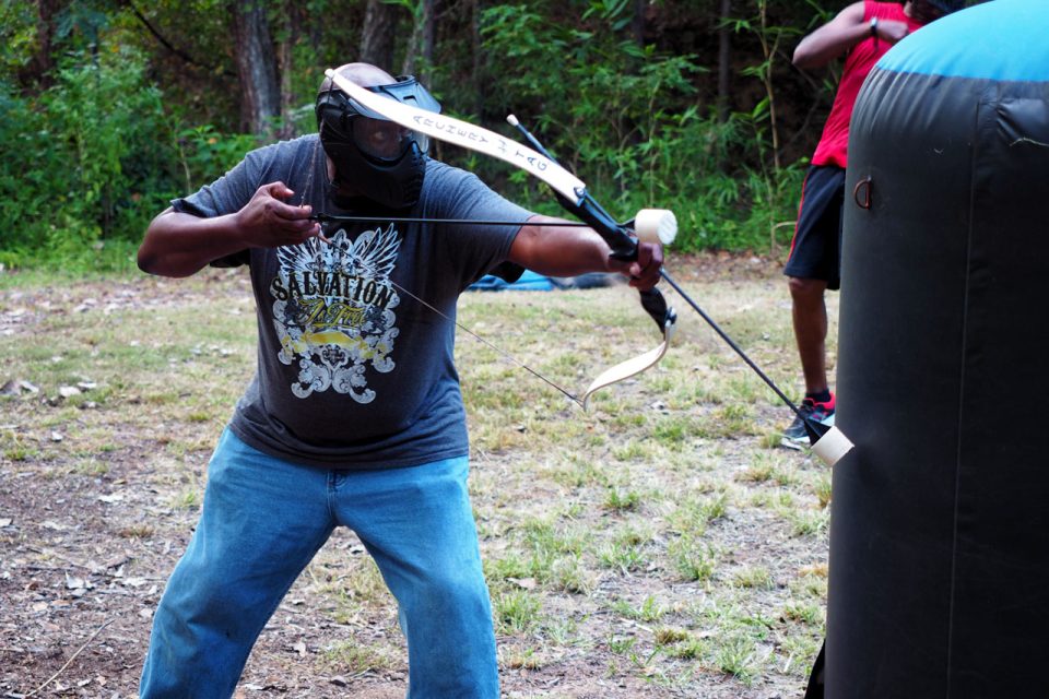 man pulls back on Archery Tag bow preparing to shoot his target