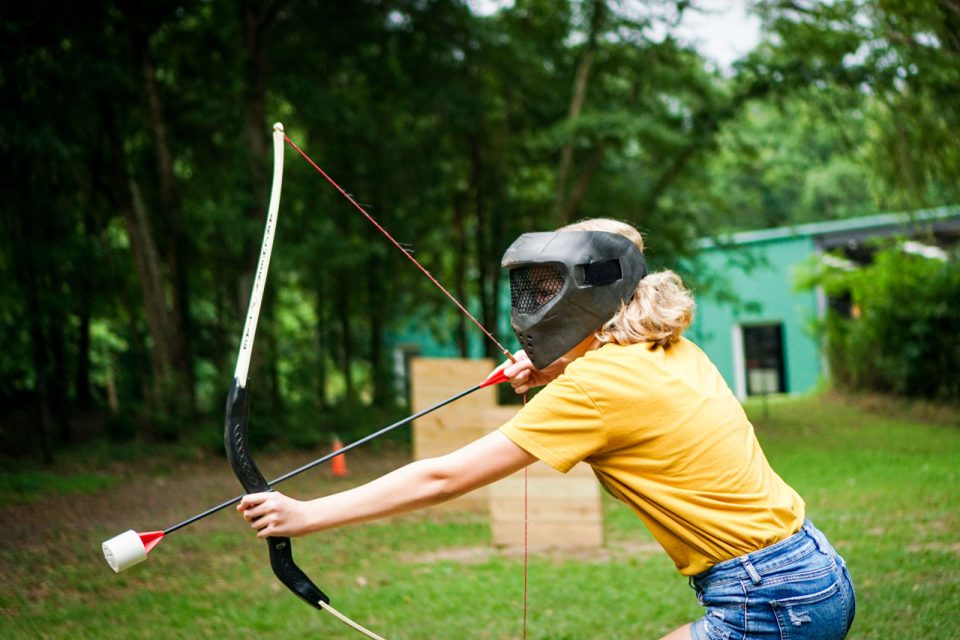 young woman in yellow shirt prepares to shoot her Archery Tag bow and arrow