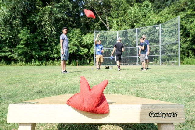 team members play corn hole on the sports fields at Camp Canaan during corporate outing