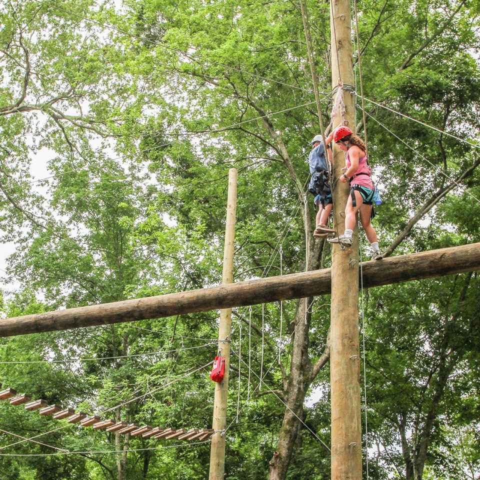 adventure guides work their way through a high ropes course element at Camp Canaan