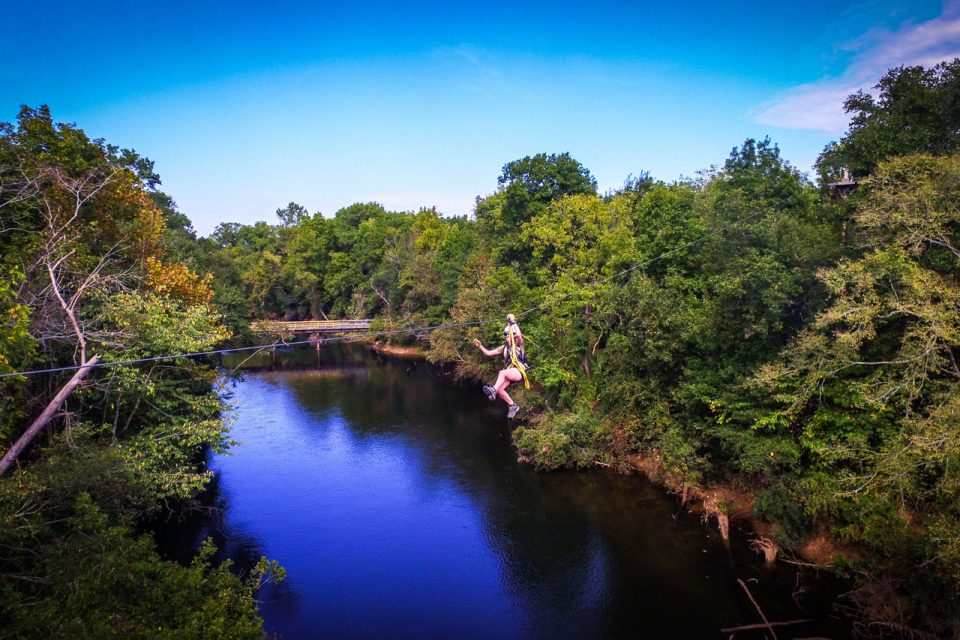 woman zips above the Catawba River on the Zipline Canopy Tour at Camp Canaan