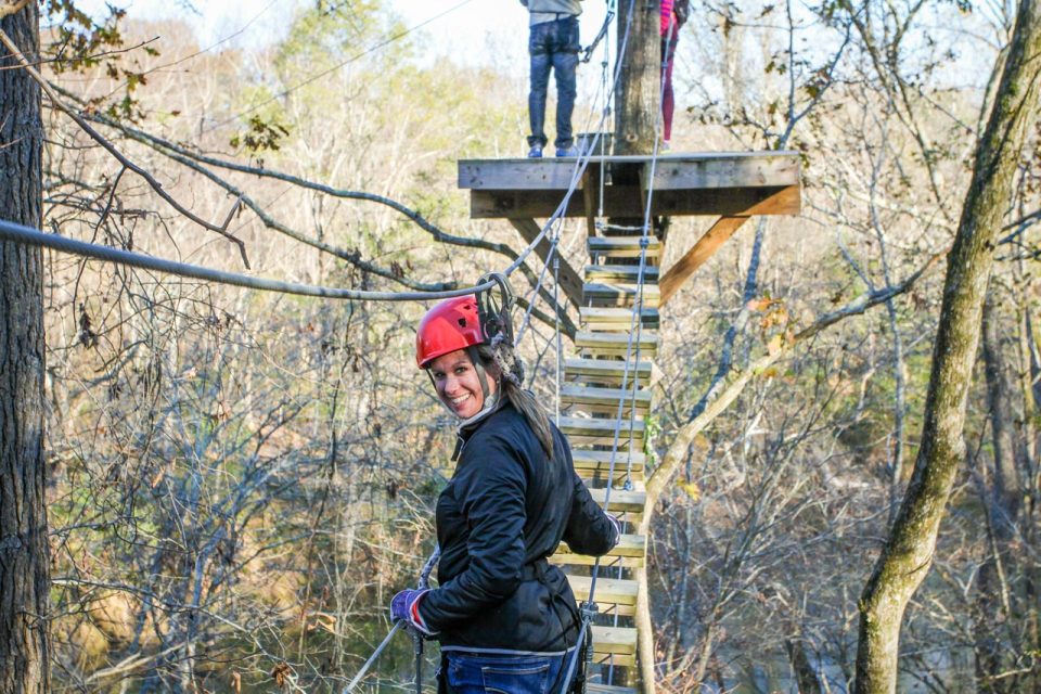 woman in red helmet walks across Harper's Ferry planks on the Zipline Canopy Tour