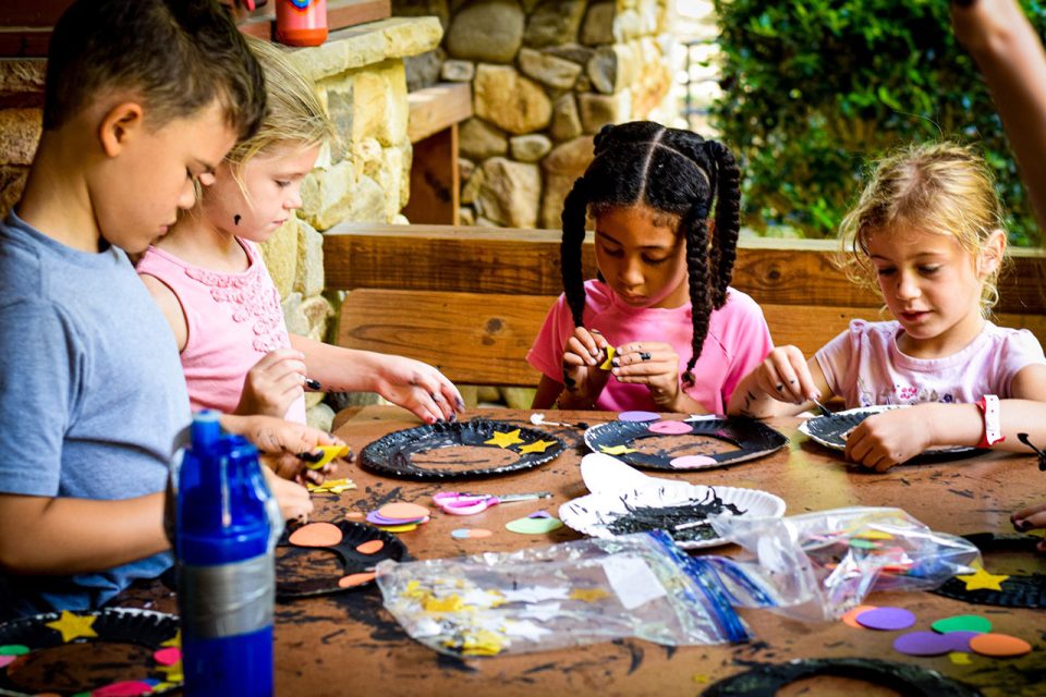 group of junior day campers focus on making their craft at Camp Canaan