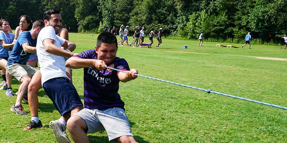 group of adults dig deep while playing tug of war for a team building exercise at Camp Canaan