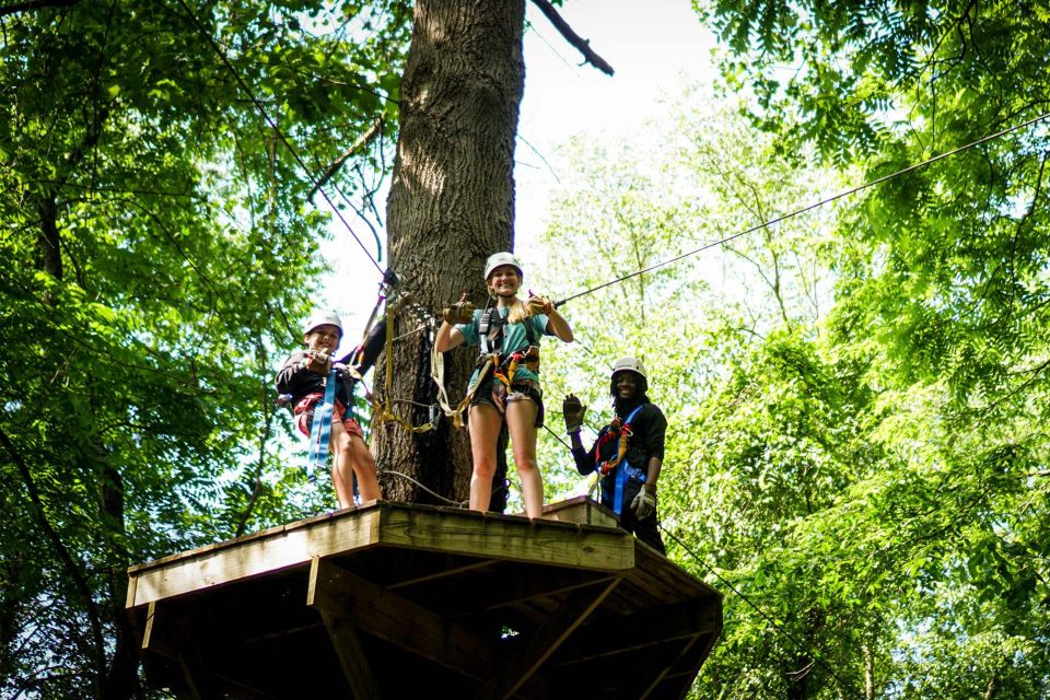 Zipline Canopy Tour guides smile down from the platform at Camp Canaan