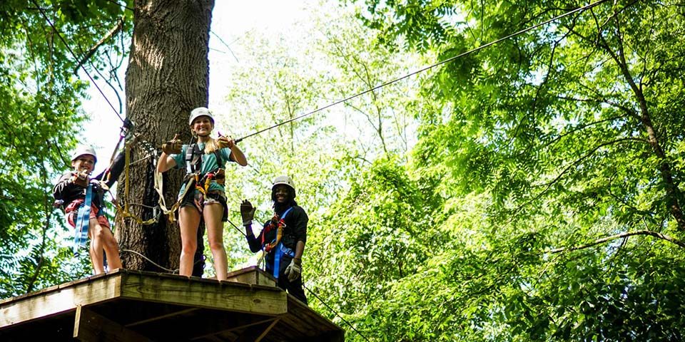 Zipline Canopy Tour guides smile down from the platform at Camp Canaan