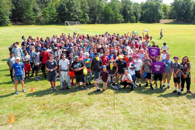 large team poses for photo in the sports fields after team building activities at Camp Canaan