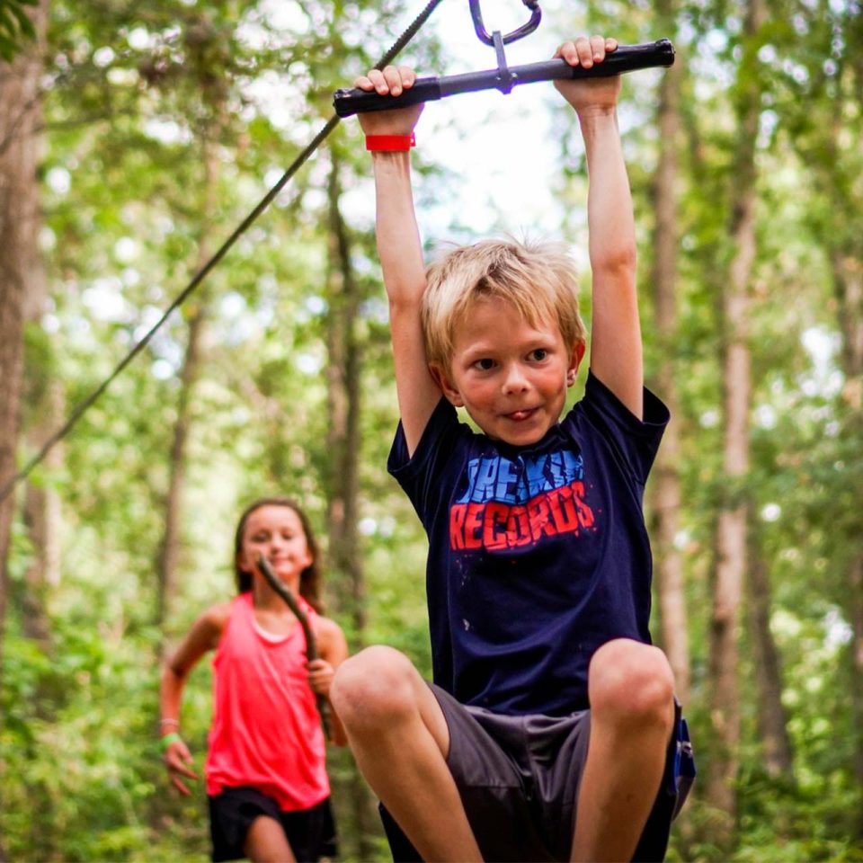 junior camper goes for a zip on the playground zipline at Camp Canaan