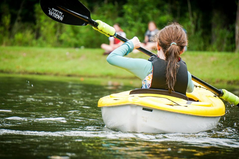 young girl kayaks around Lake Canaan in a yellow kayak