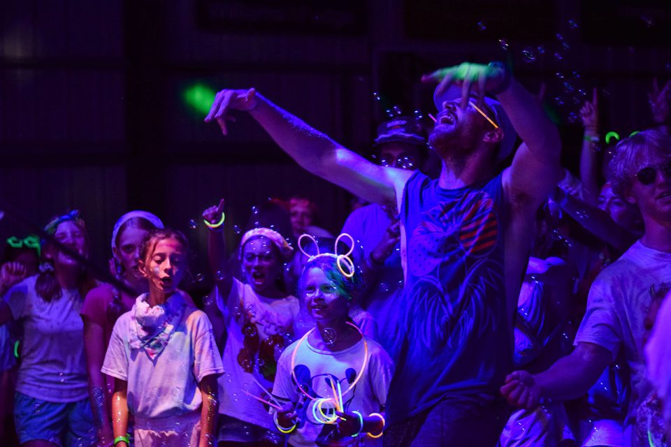 young group of campers wearing and holding glow sticks enjoy the night activities at Camp Canaan