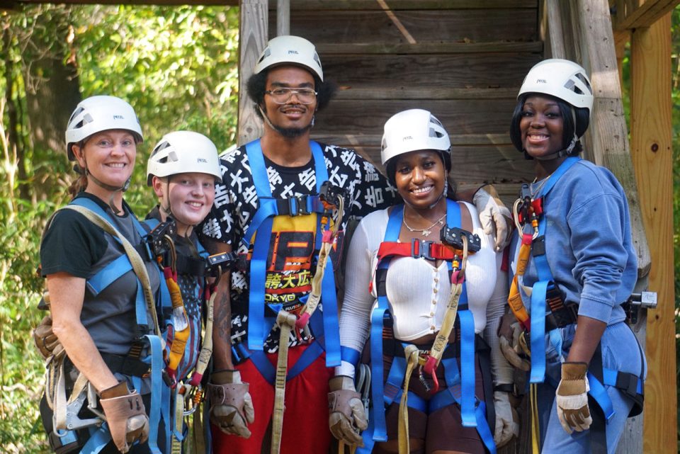 group of people in white helmets get ready to climb the zipline canopy tour tower at Camp Canaan