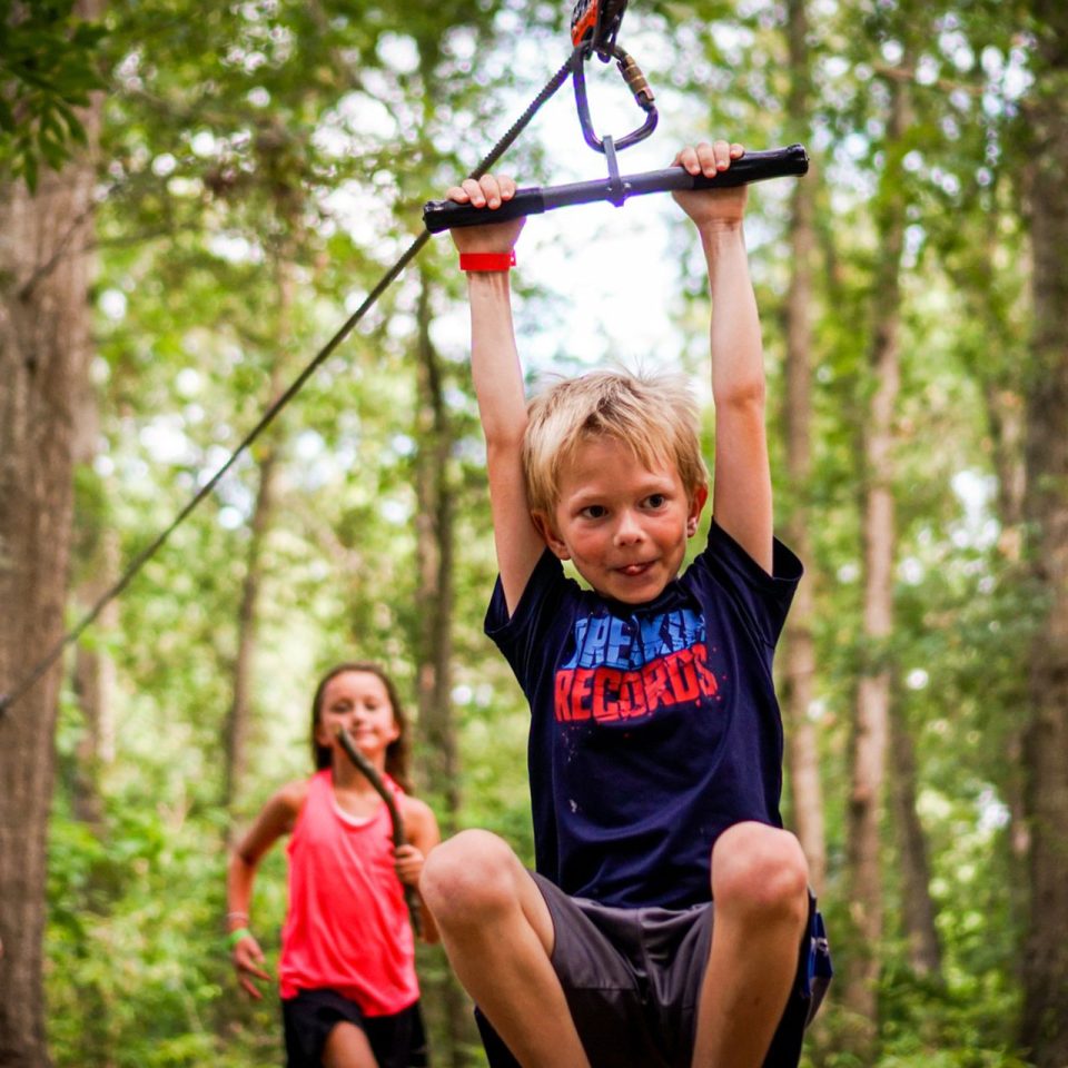 junior camper goes for a zip on the playground zipline at Camp Canaan