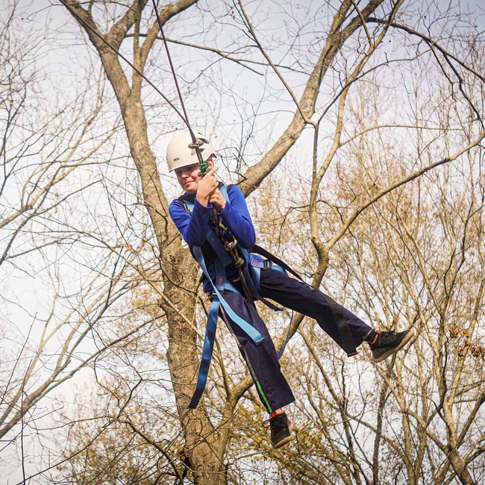 male camper in white helmet tries the zipline during winter camp