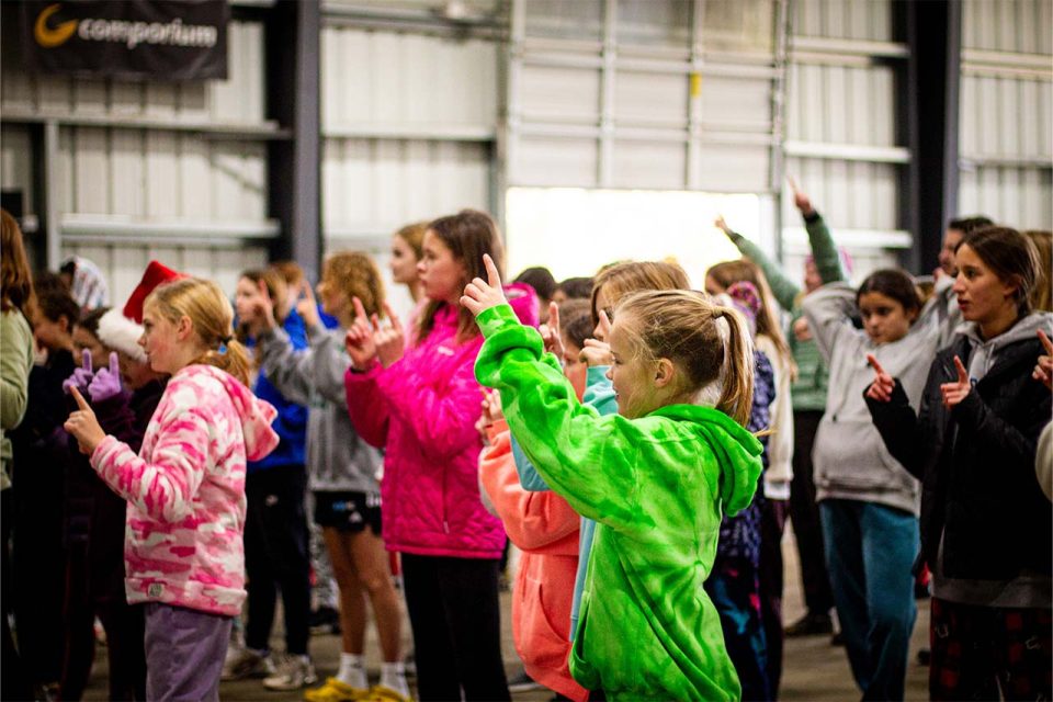 campers gather in covered basketball pavilion for evening songs at Winter Camp