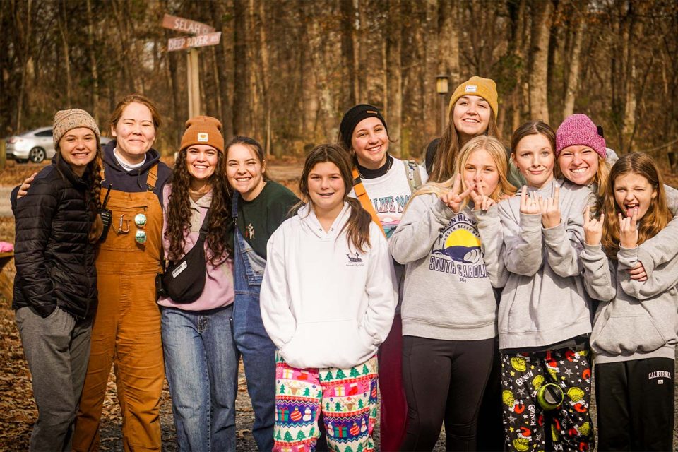 group of counselors and winter camp campers line up in front of sandy road at Camp Canaan during winter camp