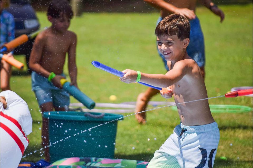 junior day camper squirts water at another camper during field games at Camp Canaan