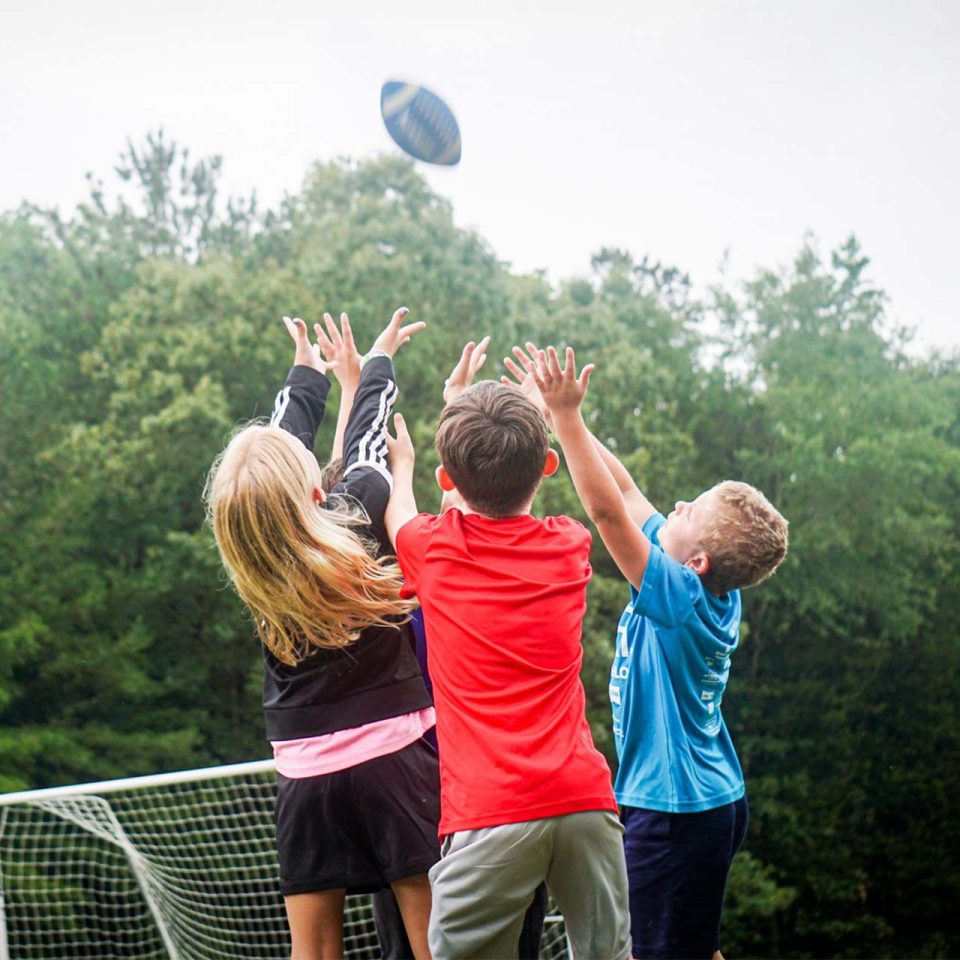 junior day campers try to catch football in sports fields at Camp Canaan