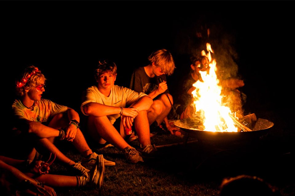 counselors sit next to bonfire at Camp Canaan