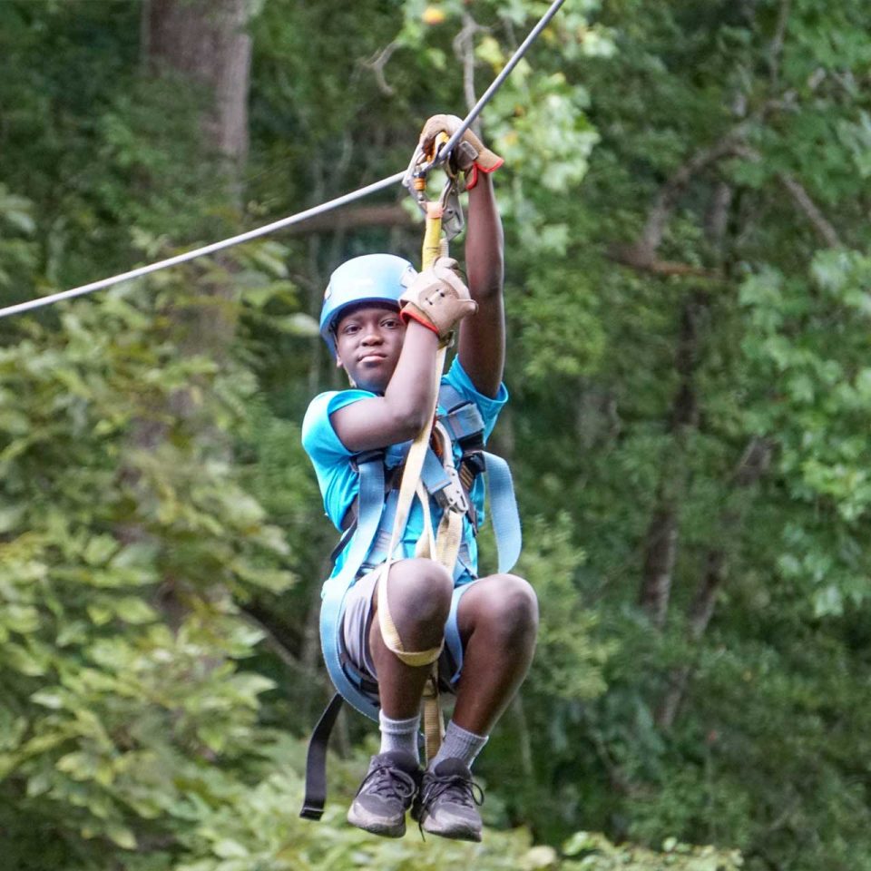 female senior day camper ziplines during summer camp at Camp Canaan