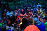 campers sit around fire pit at dusk at Camp Canaan