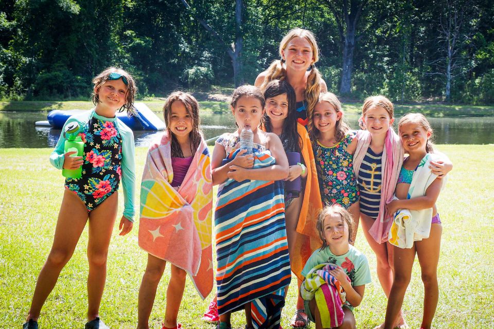 female counselor and her campers line up for photo in front of Lake Canaan