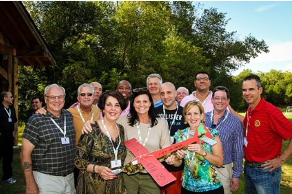 Resolute team poses for picture after enjoying airplane team building activity in picnic pavilion at Camp Canaan