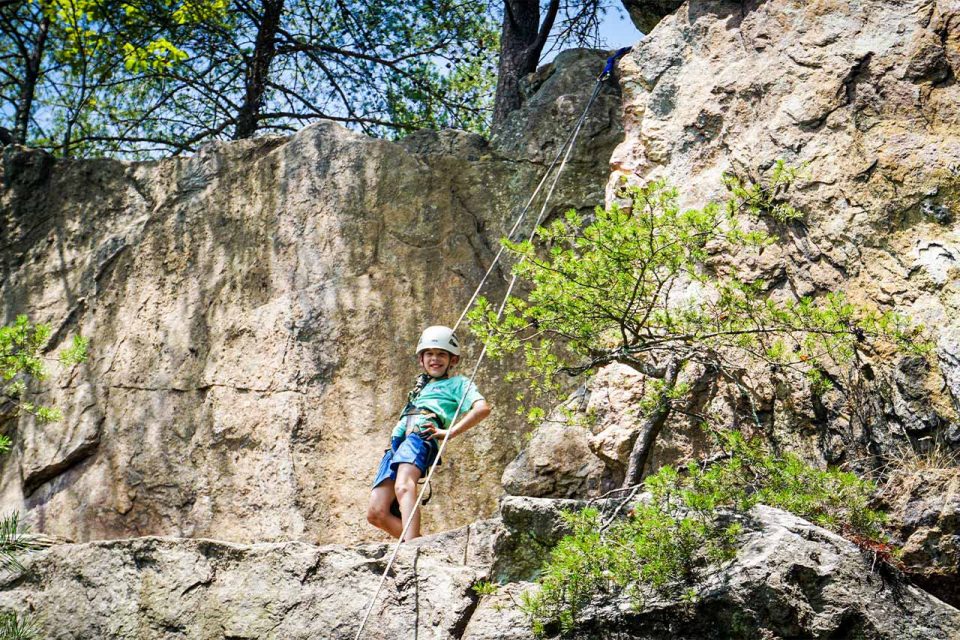 male camper in white helmet and harness gets ready to try outdoor rock climbing at Crowder's Mountain