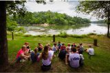 campers circle up near the river's edge to have IOT devotional time