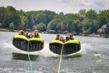 two groups of four kids tube side-by-side behind the boat in Lake Wylie trying to hold on