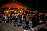 adults enjoy event standing around high top tables under cafe bulb lighting outside the multi-purpose building at Camp Canaan