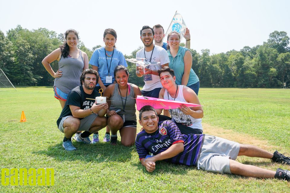 team poses with crafted airplane made during corporate team building activity at Camp Canaan