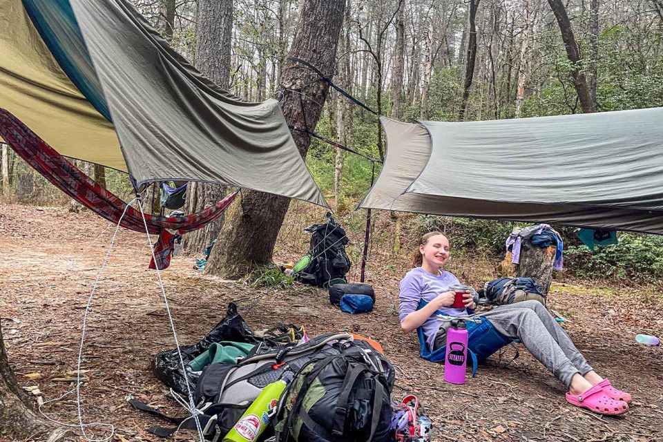 female TLC camper enjoys a beverage while sitting in camp chair