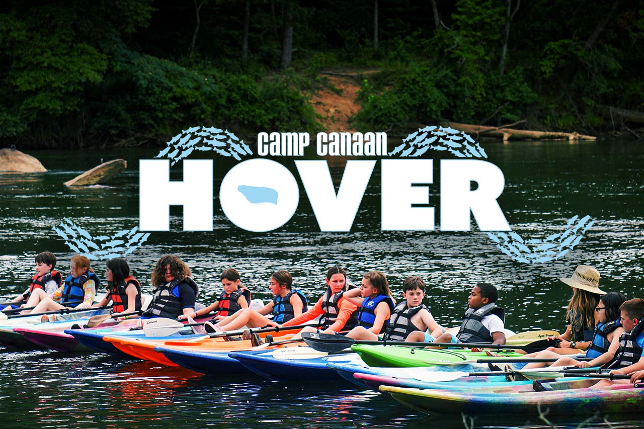 A group of young people in life jackets sit in kayaks lined up on a river, preparing to paddle. Trees and greenery surround the water. The text "Camp Canaan HOVER" is displayed prominently over the image.